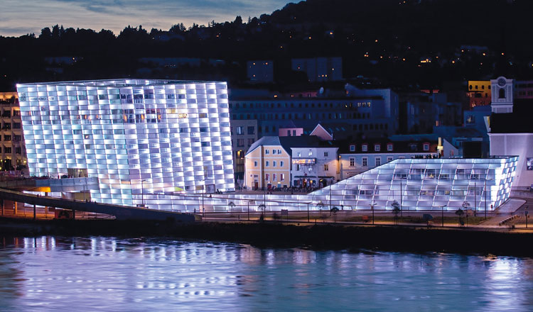 Un éclairage utilisant une technologie de pointe illumine l'enveloppe de verre d'une surface d'environ 5100 M2 autour de l'Ars Electronica Center. Les bandes de LED montées au dos des 1100 plaques de verre disposées sur la façade sont programmables séparément. La luminosité et le mélange de couleurs peuvent être réglées.